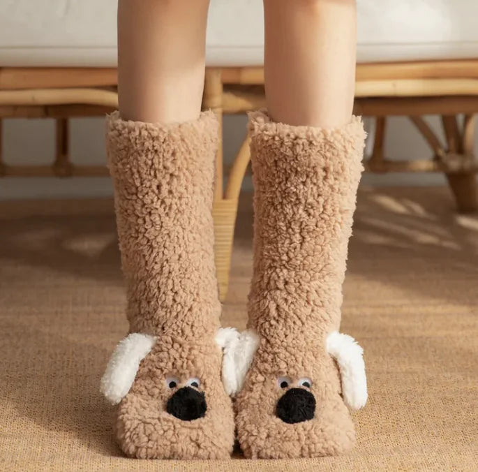 Beige dog-themed slippers worn by a person on a carpeted floor. Variety of plush dog sock colors available - black, pink, white, coffee, gray brown
