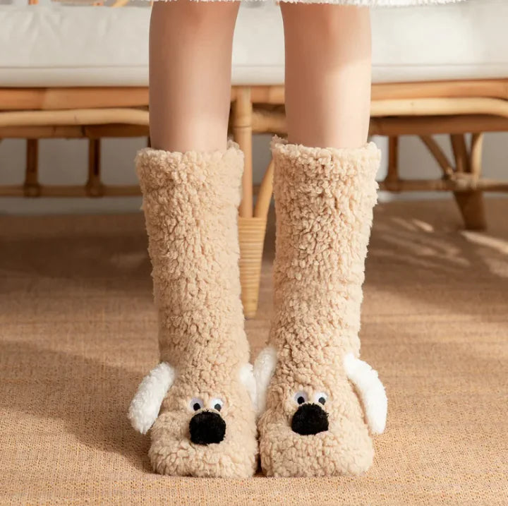 Beige fuzzy dog-shaped slippers worn indoors on a carpeted floor.